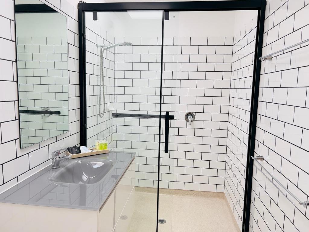 a bathroom with a sink and a glass shower at Sandpiper Motel Apollo Bay in Apollo Bay