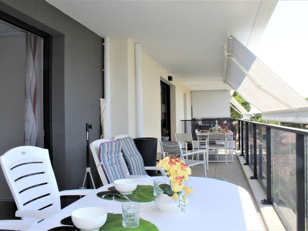 une table blanche et des chaises sur un balcon dans l'établissement Appartement Neuf 3 Pièces avec Terrasse et Garage, Cagnes-sur-Mer - FR-1-252A-88, à Cagnes-sur-Mer