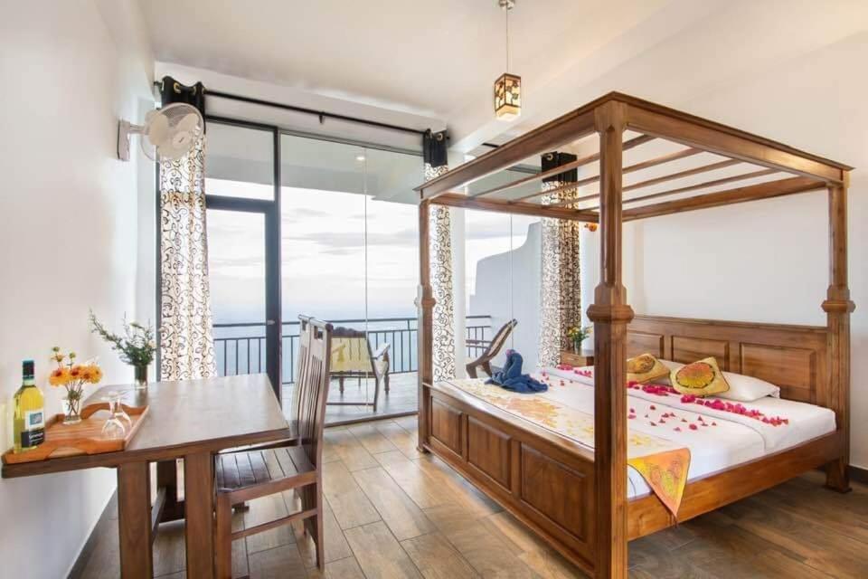a bedroom with a bed and a table and a balcony at leisure Mount View in Haputale