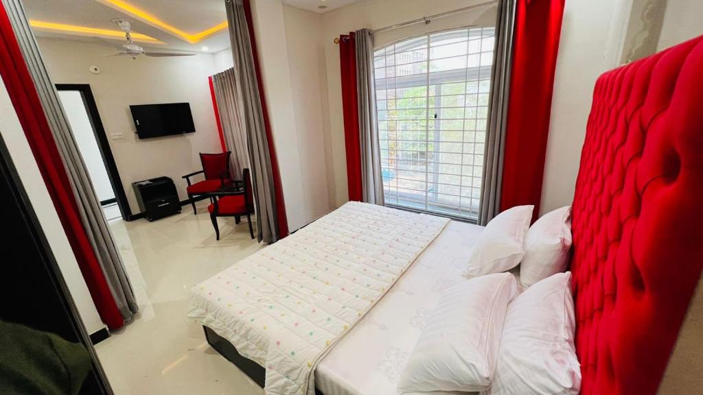 a bedroom with a red bed and a window at Hotel 11 in Islamabad