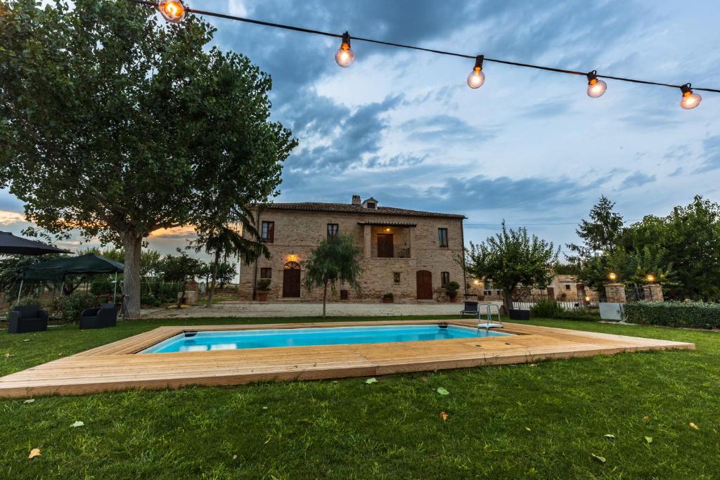 un patio trasero con piscina y una casa en BB Casale La Selva Mosciano, en Mosciano SantʼAngelo