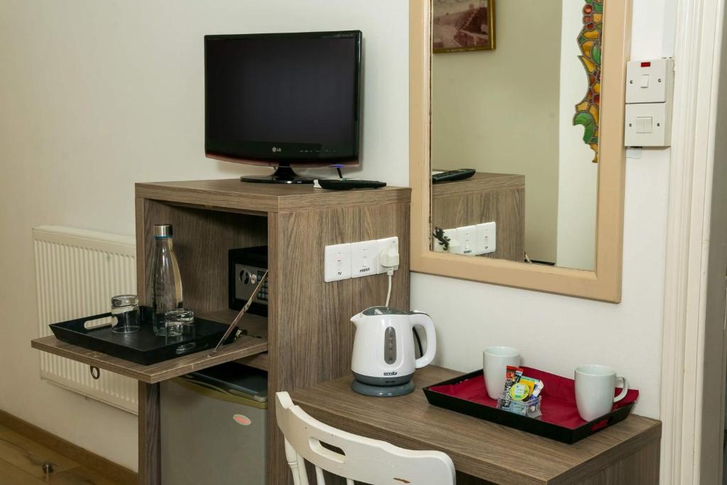 a television on a wooden stand with a table with a kettle at Fitosinn Hotel in Paphos