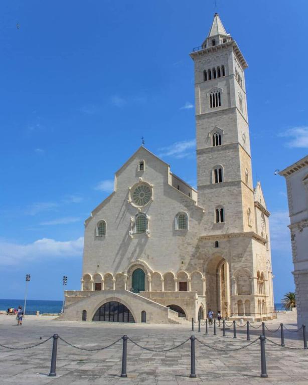 a large building with a clock tower in front of the ocean at Dimora dAmare in Trani