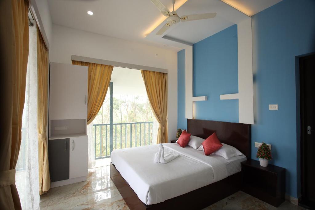 a bedroom with a bed with blue walls and a window at Paadi Holidays Idukki in Idukki