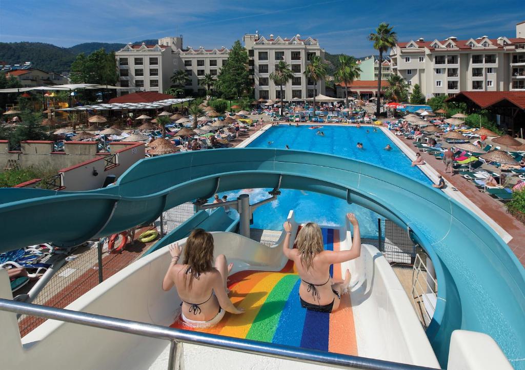 zwei Mädchen in Badeanzügen sitzen auf einer Rutsche am Pool in der Unterkunft Julian Club Hotel in Marmaris