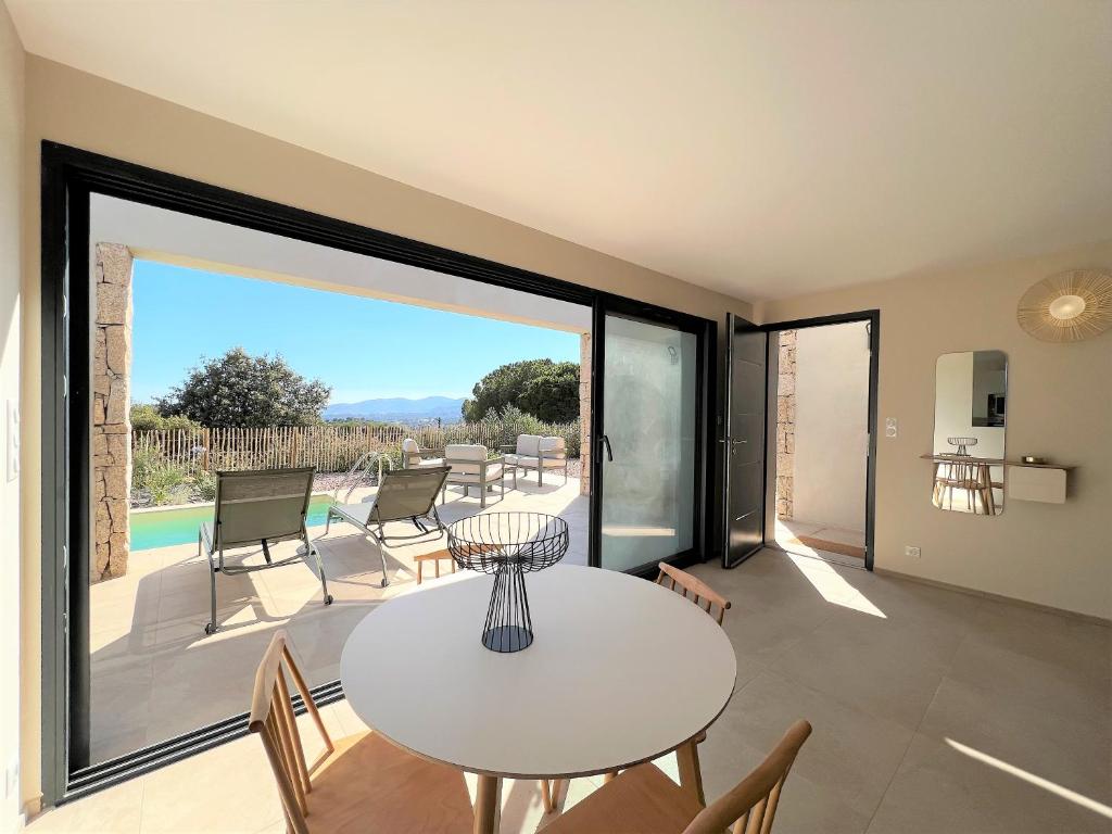 ein Wohnzimmer mit einem weißen Tisch und Stühlen in der Unterkunft Casa di Bà - villa 2 chambres avec piscine à 10 minutes des plages in 