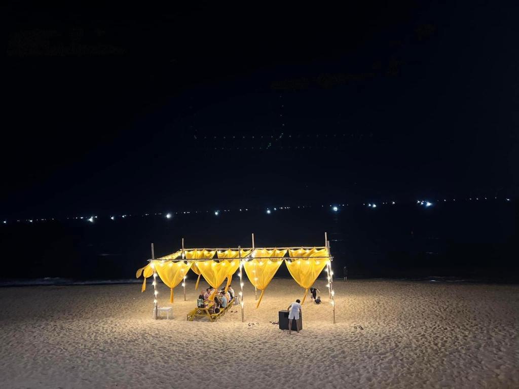 un gruppo di persone seduti sotto una tenda sulla spiaggia di Nana Lee Homestay & Restaurant Quảng Bình a Dong Hoi