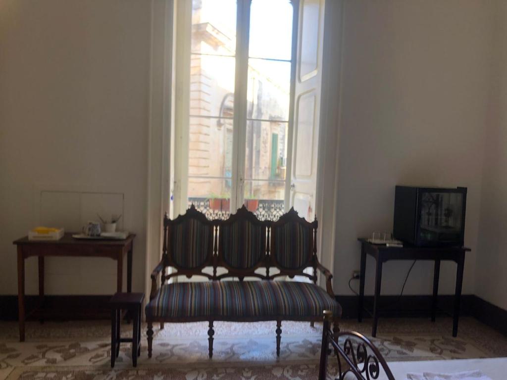 a room with a chair in front of a window at Palazzo Bernardini Suites in Lecce