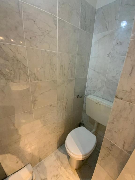 a bathroom with a toilet and a tiled wall at Hotel Naviglio in Marina di Pietrasanta