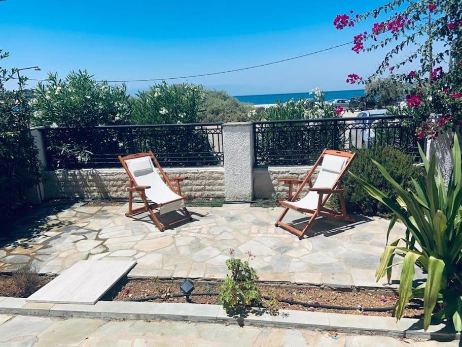 2 chaises assises sur une terrasse avec l'océan en arrière-plan dans l'établissement Familienfreundliches Fischerhaus am Strand, à Porto Heli
