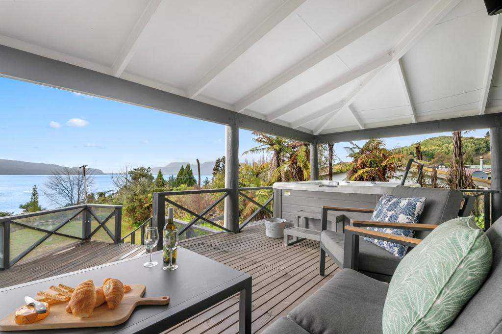 a patio with a table and a tub on a deck at Splendour on Spencer - Lake Tarawera Holiday Home in Lake Tarawera