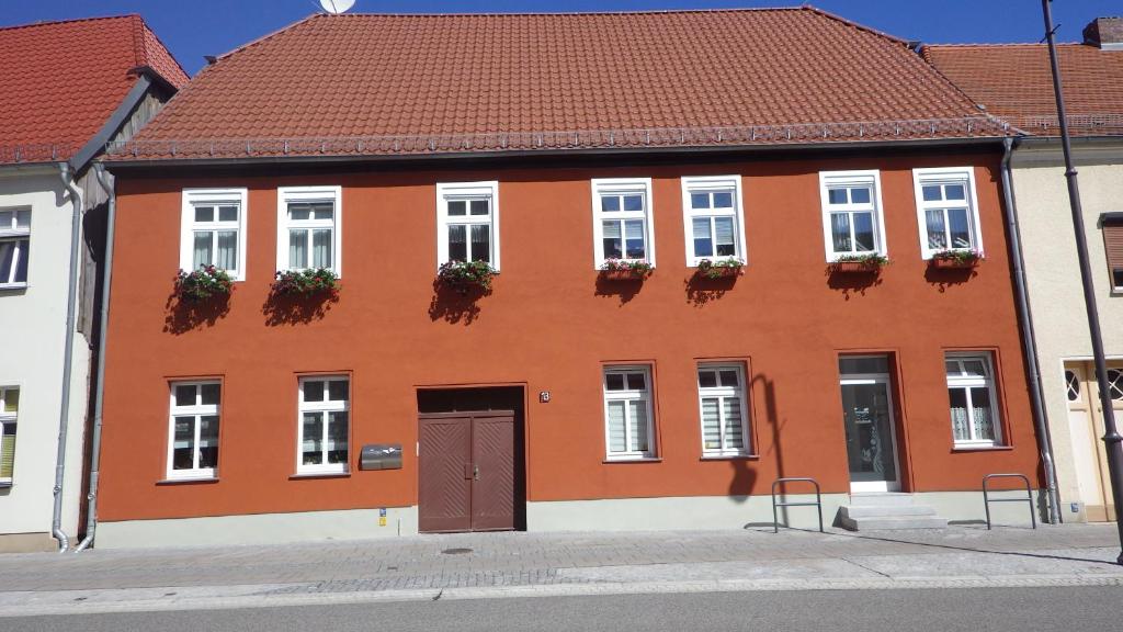 a orange building with white windows and a brown door at Ferienwohnung Große / Werner in Jüterbog