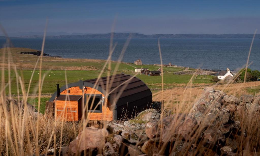 a boat sitting on top of a hill next to the ocean at Culkein Pods in Lochinver