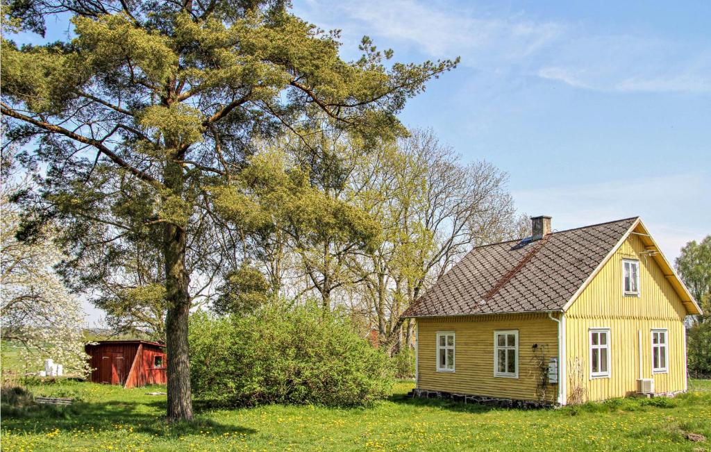 une petite maison jaune dans un champ avec un arbre dans l'établissement 1 Bedroom Awesome Home In Vinslv, à Vinslöv