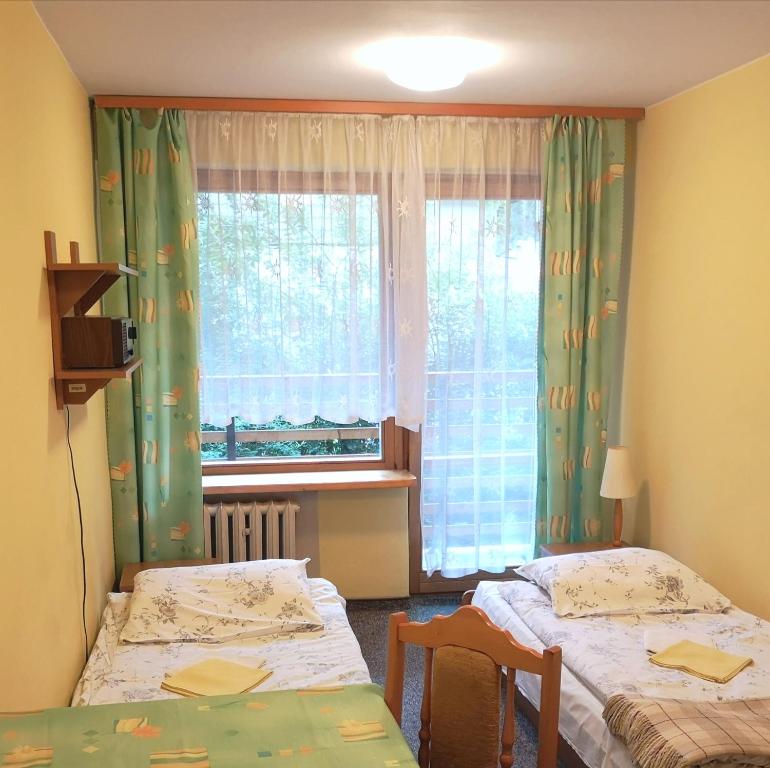 a small room with two beds and a window at Ośrodek Szpulki in Zakopane