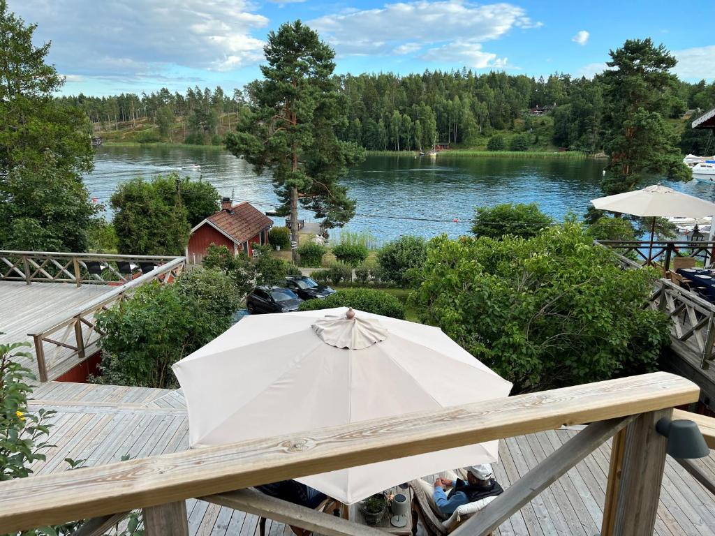 a white umbrella sitting on a deck next to a lake at Exclusive guesthouse with stunning Seaview! in Värmdö