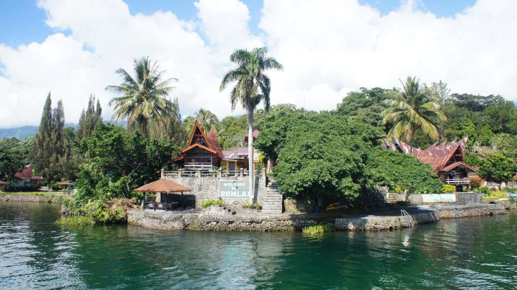 a house on a island in the water with palm trees at Romlan in Tuktuk Siadong