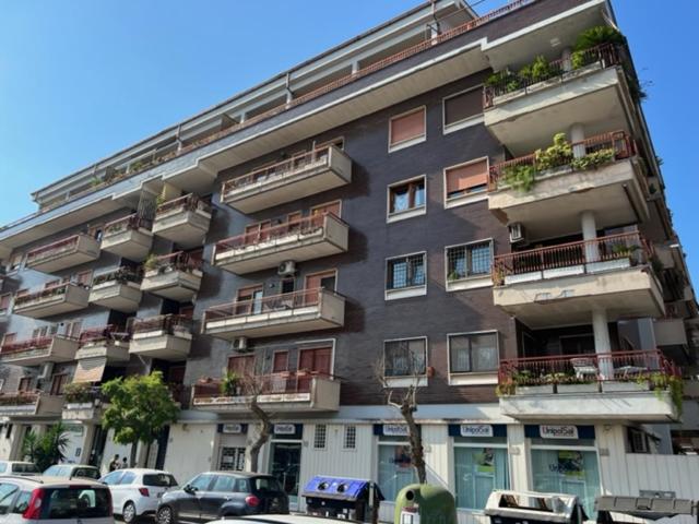 wysoki budynek z samochodami zaparkowanymi przed nim w obiekcie LA CASA DI ALICE 2 w mieście Lido di Ostia