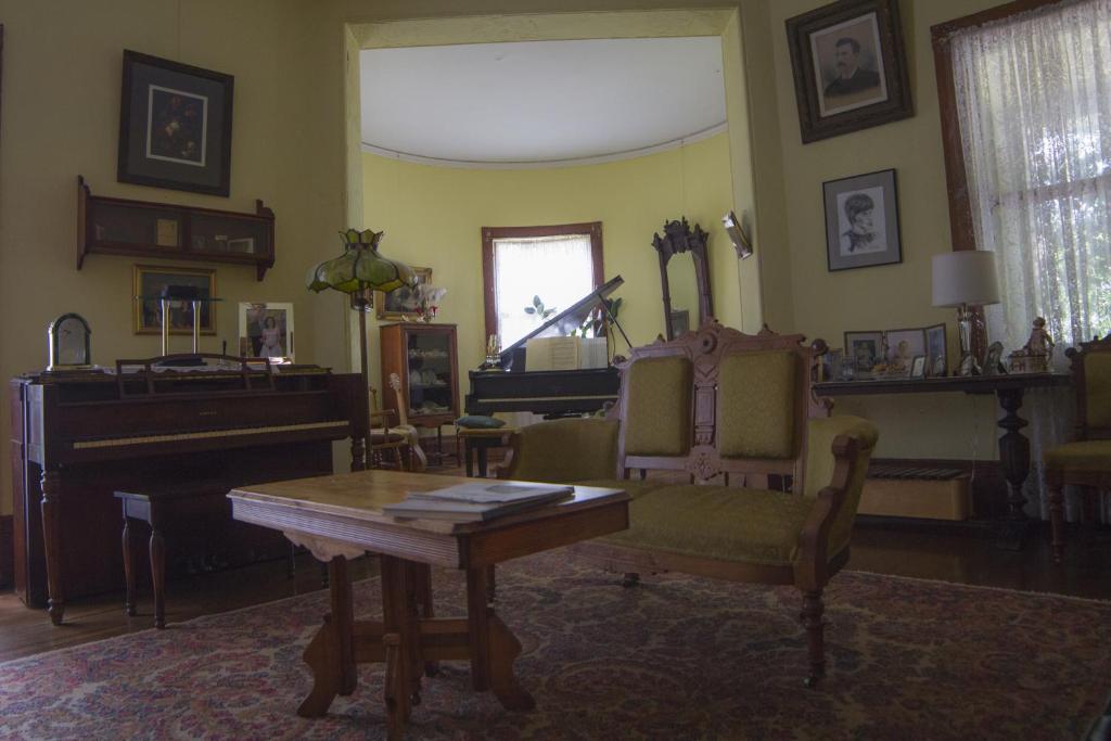 Lehmann House Bed & Breakfast في سانت لويس: غرفة معيشة فيها بيانو وطاولة