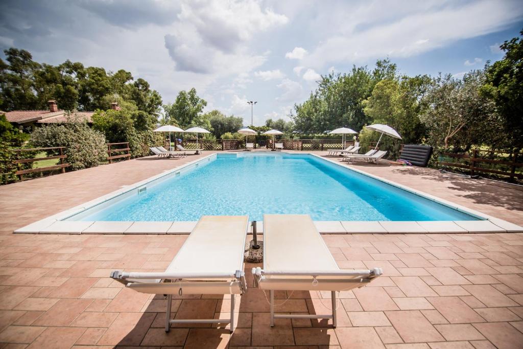 uma piscina com duas espreguiçadeiras ao lado em Agriturismo Le Giare em Bagno Roselle