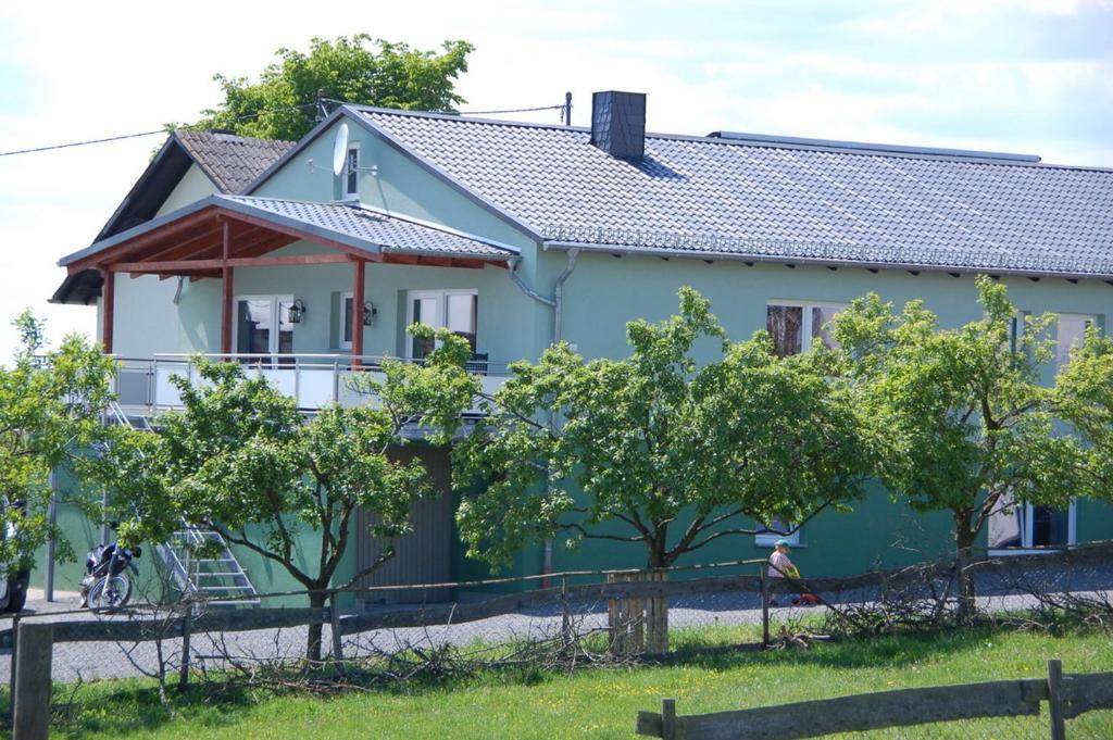 ein blaues Haus mit Bäumen davor in der Unterkunft Ferienwohnungen Landgasthaus Janshen in Ellscheid