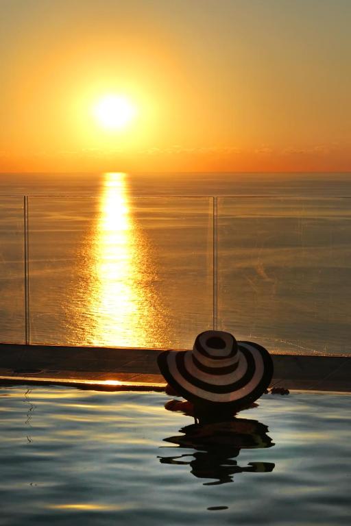 une piscine avec le soleil couchant sur l'océan dans l'établissement Villa DAMMUSO by Local House - private villa infinity pool & seaview, à Santo Stefano di Camastra