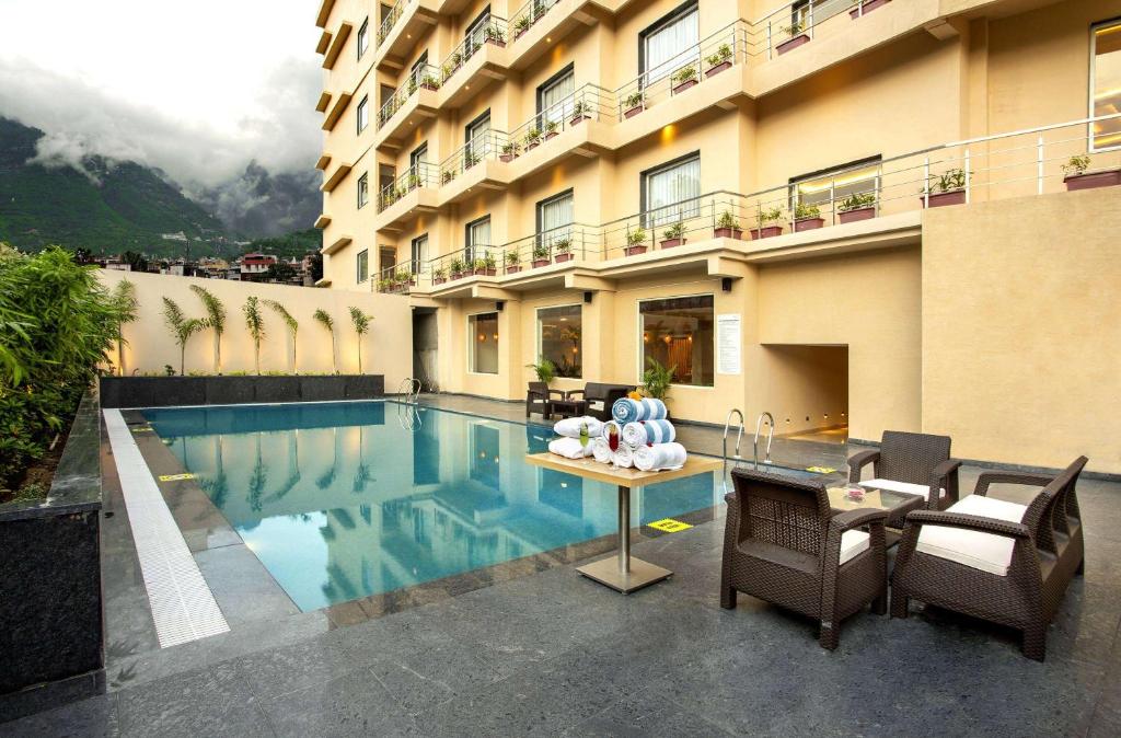 un hôtel avec une piscine en face d'un bâtiment dans l'établissement Ramada by Wyndham Katra Station Road, à Katra