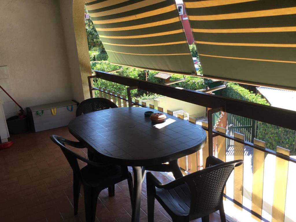 a black table and chairs on a balcony with a window at Appartamento a Marina di San Nicola Roma in Palo