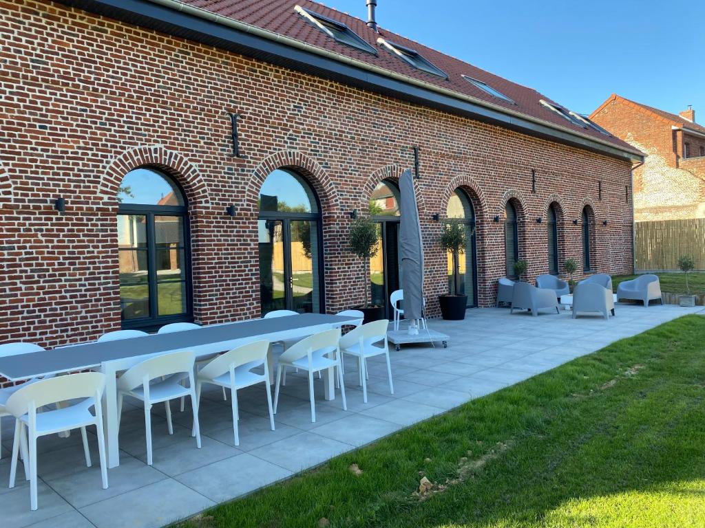 a brick building with a table and chairs on a patio at LA GRANGE in Anzin-Saint-Aubin