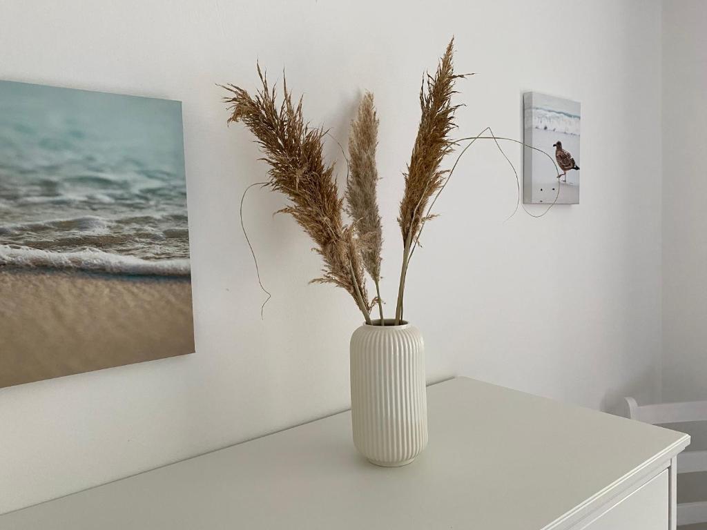 a white vase with a plant in it on a table at Strandlächeln Lodge - Ferienwohnung mit 2 Schlafzimmern in Hohenfelde