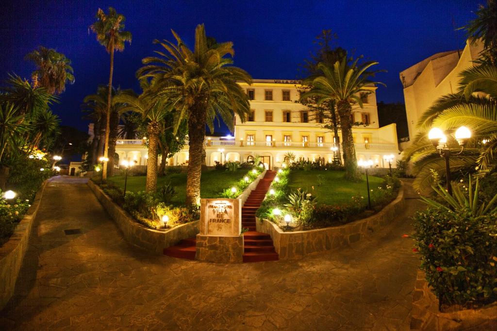 un edificio con palmeras y luces por la noche en Grand Hotel Villa de France, en Tánger