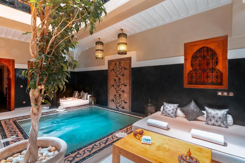 a pool in a villa with a tree and a couch at Riad Rodaina in Marrakesh