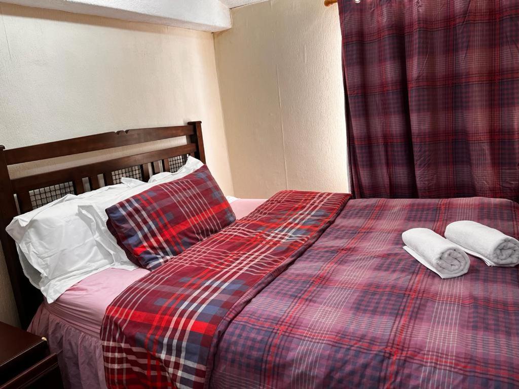 a bed with two pillows and a plaid blanket at BLACKPOOL MERCY Inn HOTEL in Blackpool