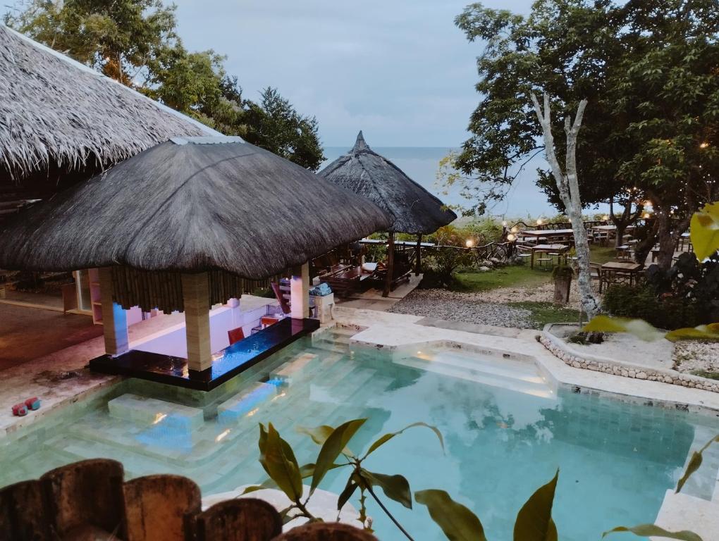 een zwembad in een resort met een rieten dak bij Tahanan Resort in San Juan