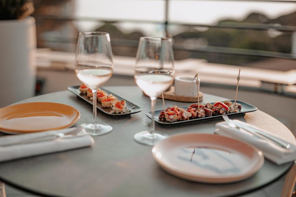 a table with two glasses of wine and plates of food at The 1932 Hotel & Spa Cap d'Antibes - MGallery Collection in Juan-les-Pins