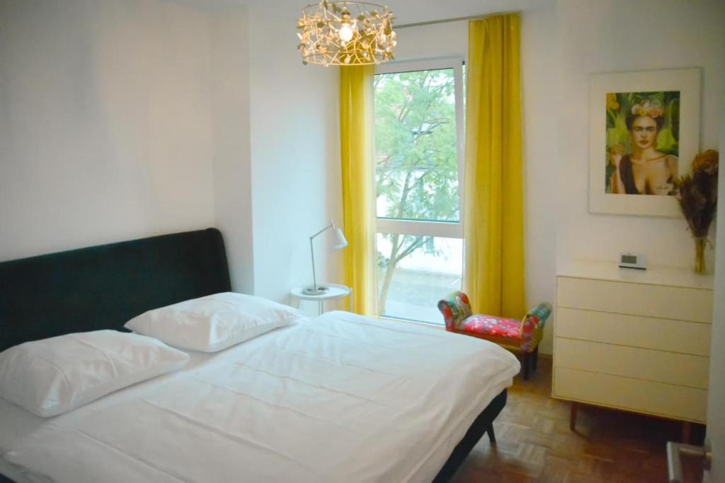 a bedroom with a bed with a chandelier and a window at StellaStudio in Hamburg