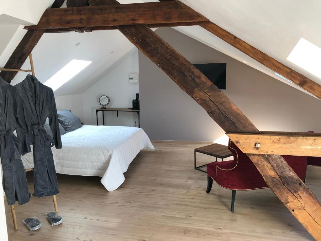 - une chambre mansardée avec un lit et une chaise dans l'établissement Les 3 p’tites pom’s, à Aleçon