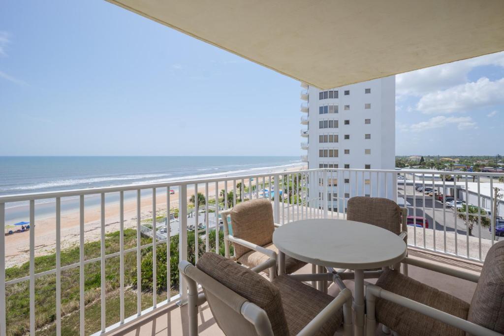 a balcony with a table and chairs and the beach at Sea Winds 501 - Corner Breeze in Ormond Beach