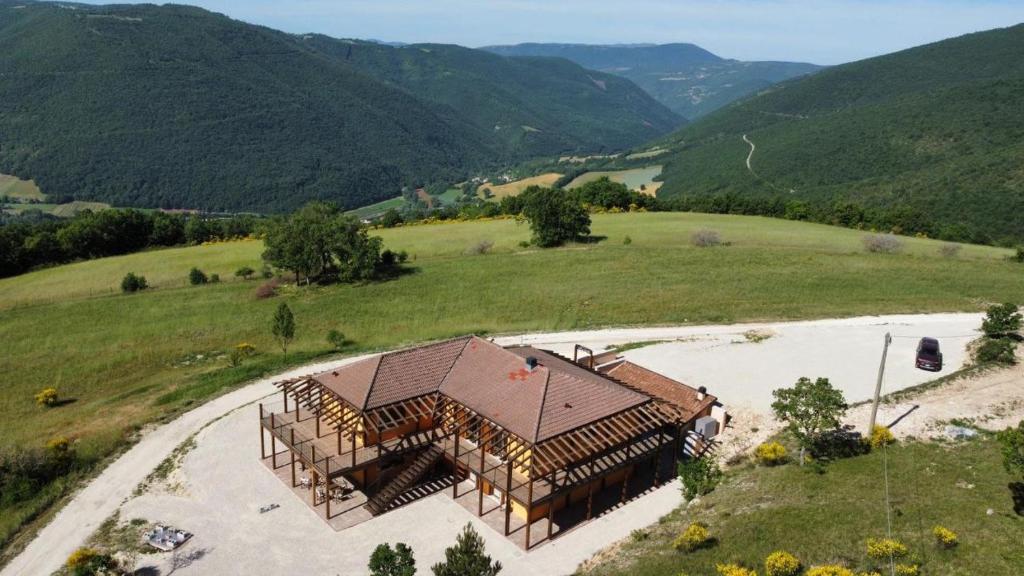 a house in a field with mountains in the background at Casale Sienti'n Può in Norcia