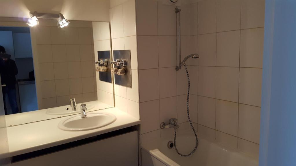 a bathroom with a sink and a shower with a mirror at FeWo Hostel in Cologne