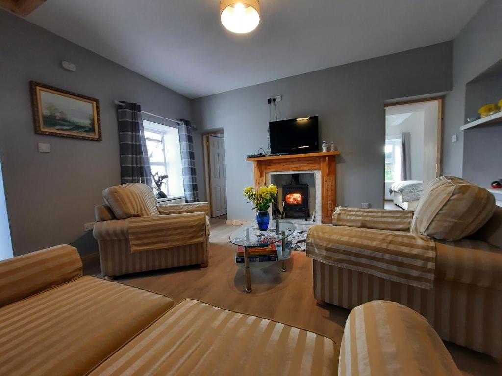 a living room with couches and a fire place at Conneelys Cottage, Connemara, Clifden, H71Y096 in Clifden