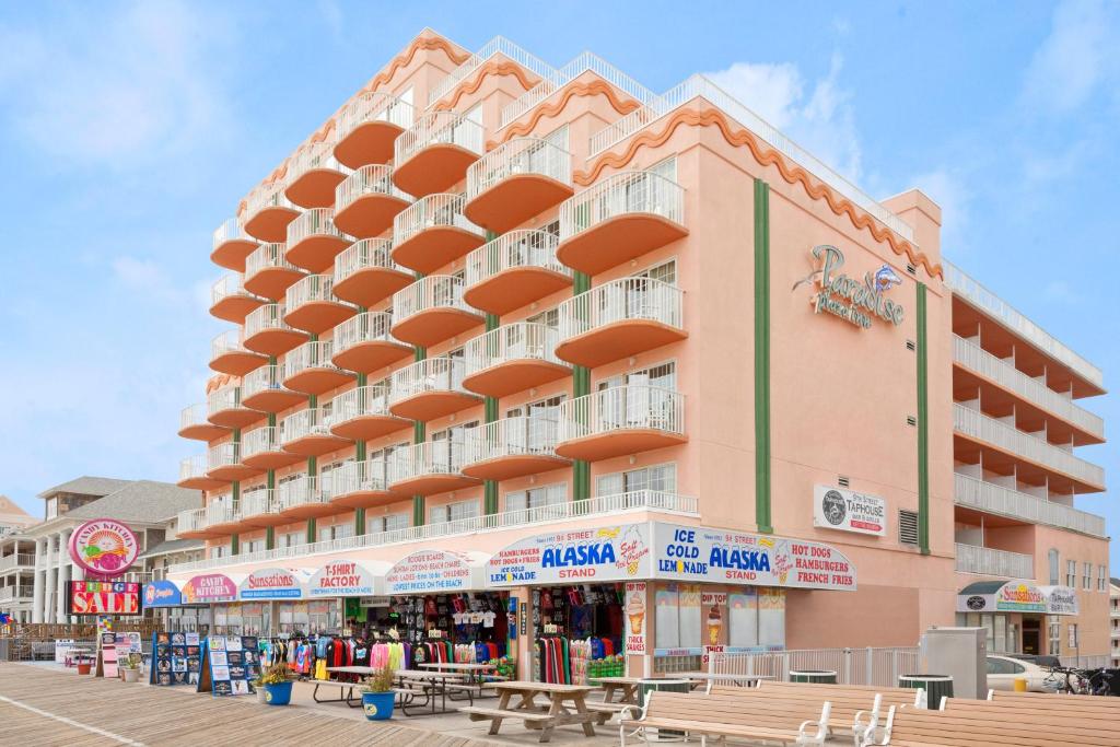 een groot roze gebouw met tafels ervoor bij Paradise Plaza Inn in Ocean City