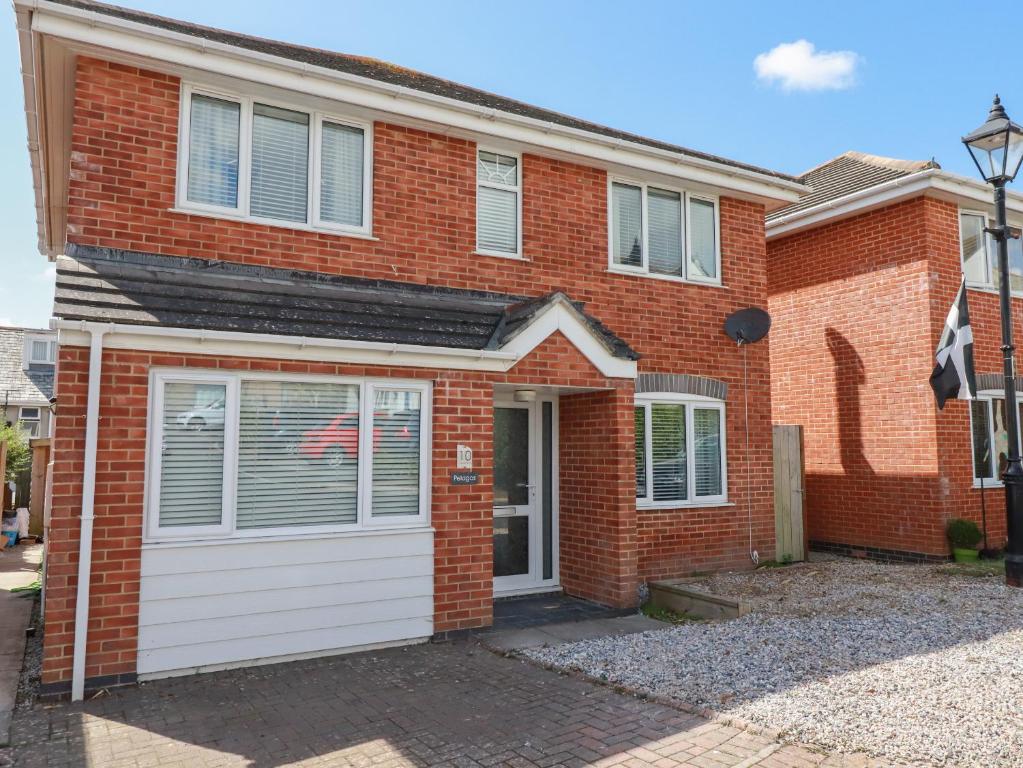 a red brick house with a white garage at Pelagos in Bude