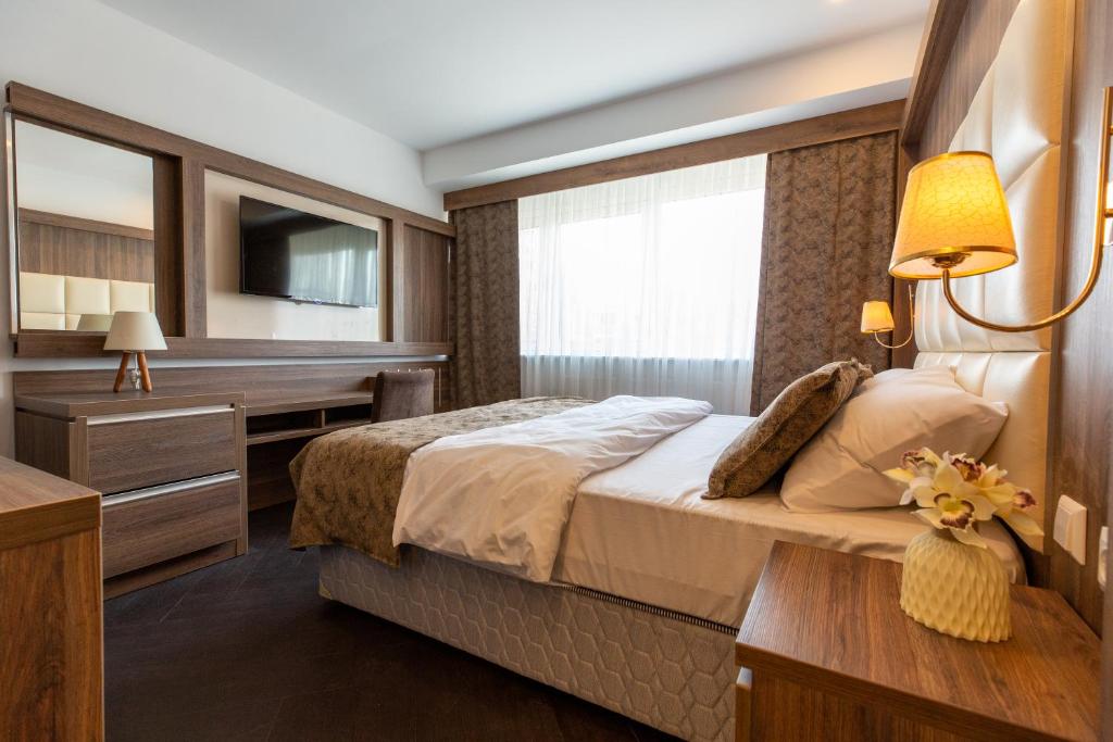 a bedroom with a bed and a desk and a television at Hotel Cataleya in Almere