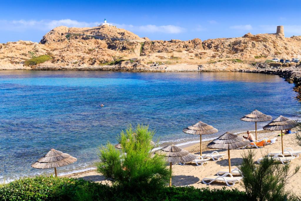 uma praia com guarda-sóis e cadeiras e o oceano em Best Western Premier Santa Maria em LʼÎle-Rousse