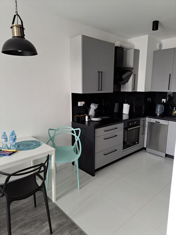 cocina con mesa, mesa blanca y sillas en Apartament Morski, en Koszalin