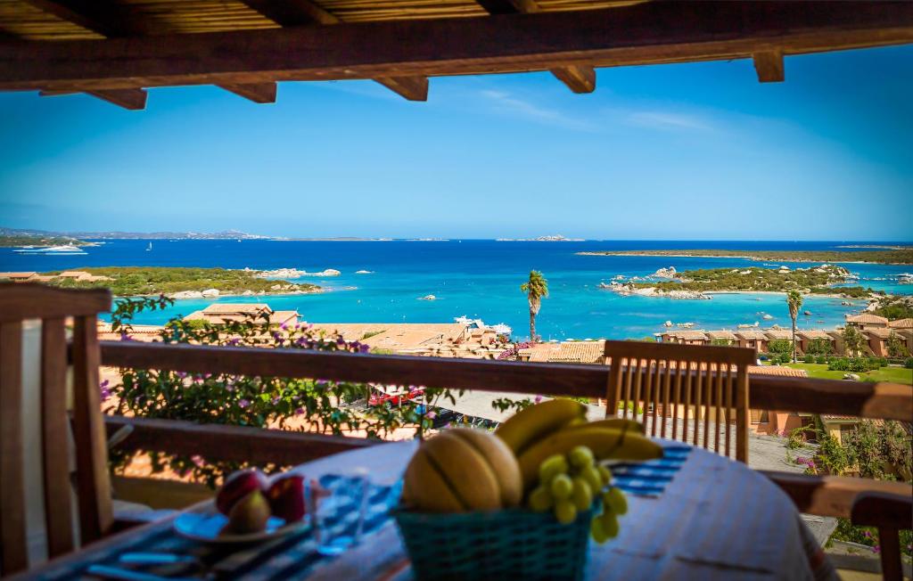 a table with a bowl of fruit on a balcony with a beach at Appartamenti Marineledda Golfo di Marinella in Golfo Aranci
