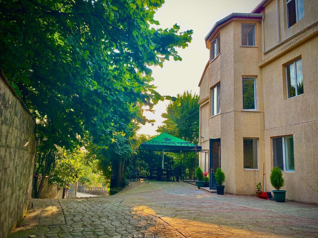 a cobblestone street in front of a building with a green umbrella at Guest House Sophie in Gonio