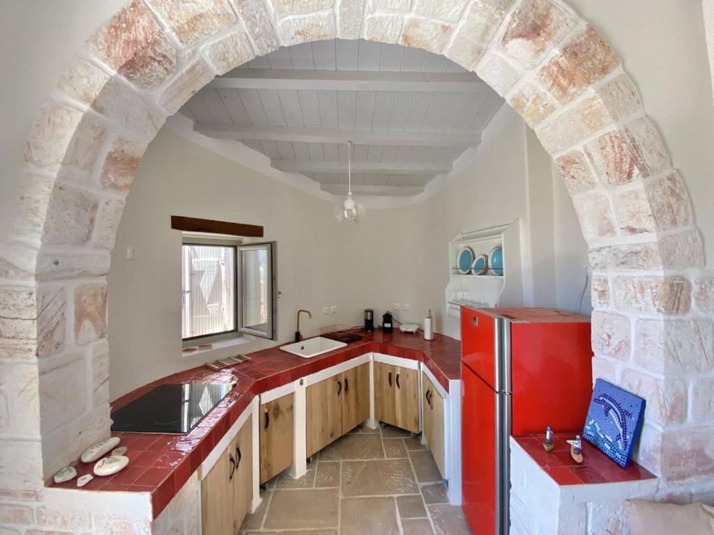 an archway in a kitchen with a red refrigerator at Fournos in Kimolos