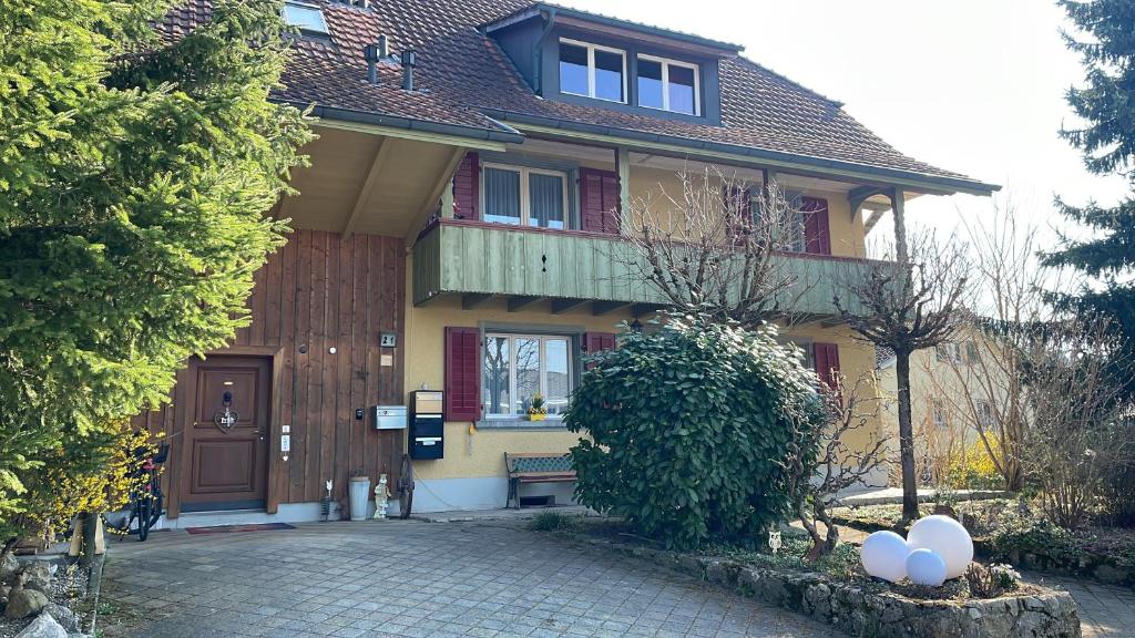 a yellow house with a porch and a balcony at Bed-International in Roggwil